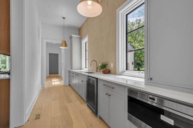 kitchen with wine cooler, visible vents, stainless steel microwave, a sink, and plenty of natural light