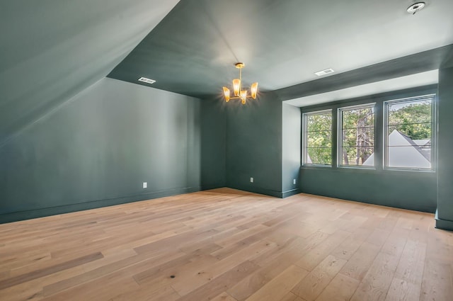 spare room with visible vents, a chandelier, and wood finished floors