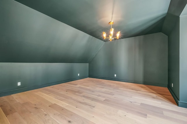 bonus room featuring lofted ceiling, an inviting chandelier, baseboards, and wood finished floors