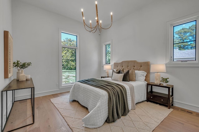 bedroom featuring a chandelier, light wood finished floors, visible vents, and baseboards