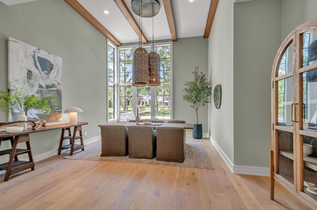 dining area with hardwood / wood-style flooring, a high ceiling, baseboards, and beam ceiling