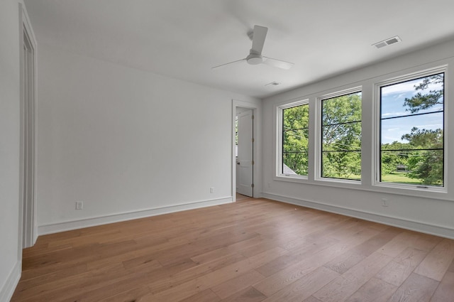 spare room with a ceiling fan, light wood-style flooring, visible vents, and baseboards