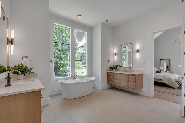 ensuite bathroom featuring ensuite bathroom, vanity, a chandelier, a freestanding tub, and baseboards