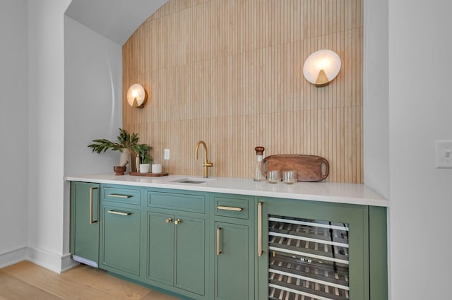 bar featuring wine cooler, a sink, baseboards, light wood-type flooring, and indoor wet bar