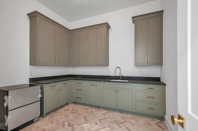 kitchen featuring dark countertops, green cabinets, and a sink