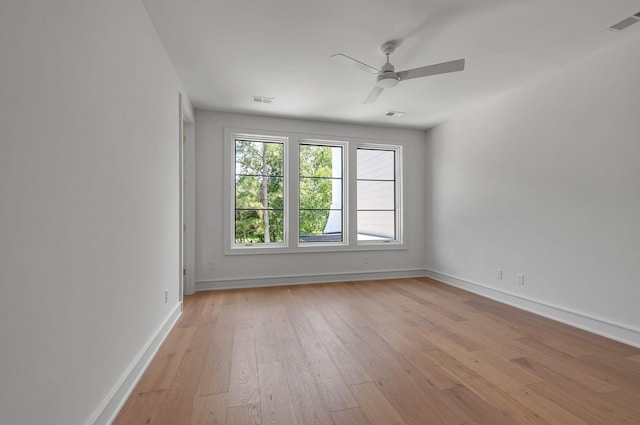 empty room featuring a ceiling fan, light wood-type flooring, visible vents, and baseboards