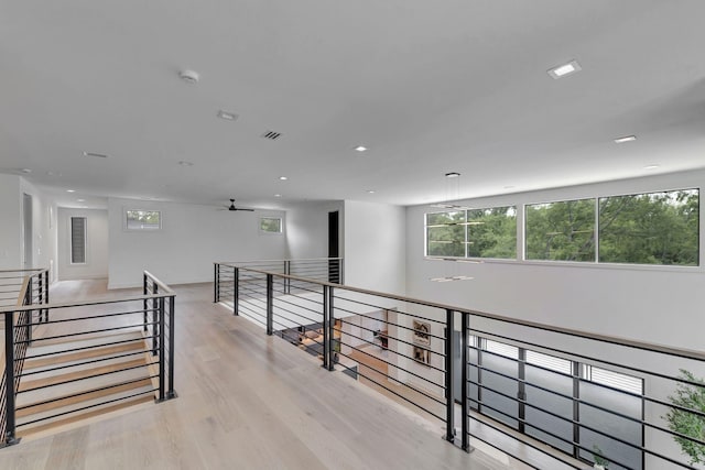 corridor with visible vents, light wood finished floors, an upstairs landing, and recessed lighting