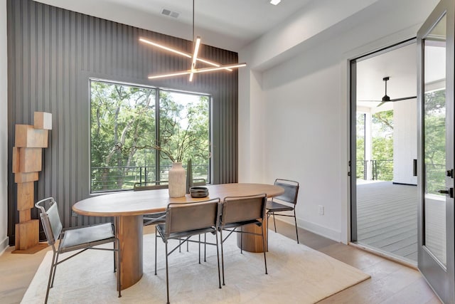 dining room with a chandelier, baseboards, visible vents, and light wood finished floors