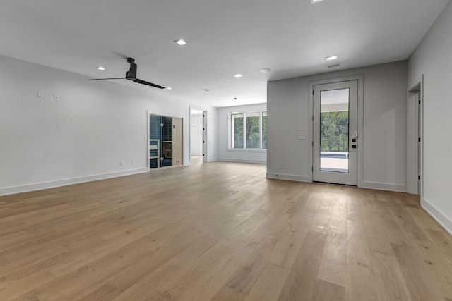 unfurnished living room with a ceiling fan, light wood-type flooring, and baseboards