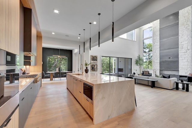 kitchen with a sink, modern cabinets, light brown cabinets, and a large island with sink