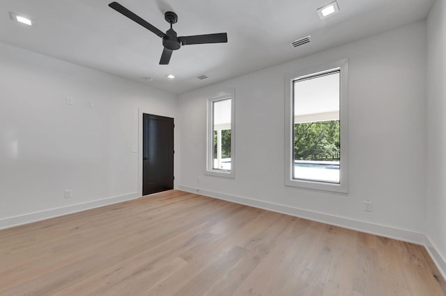 spare room featuring a ceiling fan, light wood-type flooring, visible vents, and baseboards