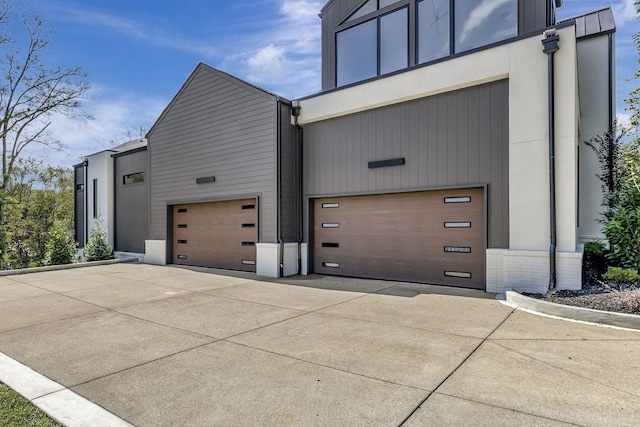 view of side of property featuring driveway, brick siding, and an attached garage