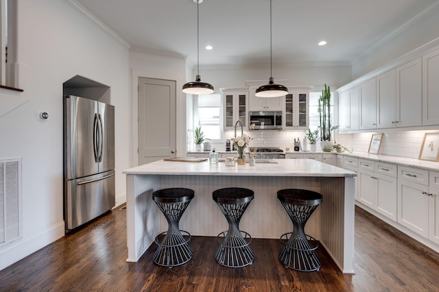 kitchen with backsplash, appliances with stainless steel finishes, and ornamental molding