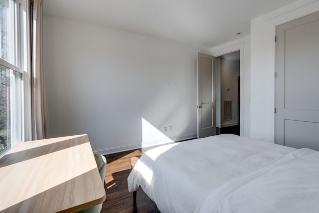 bedroom with visible vents, multiple windows, dark wood-type flooring, and baseboards