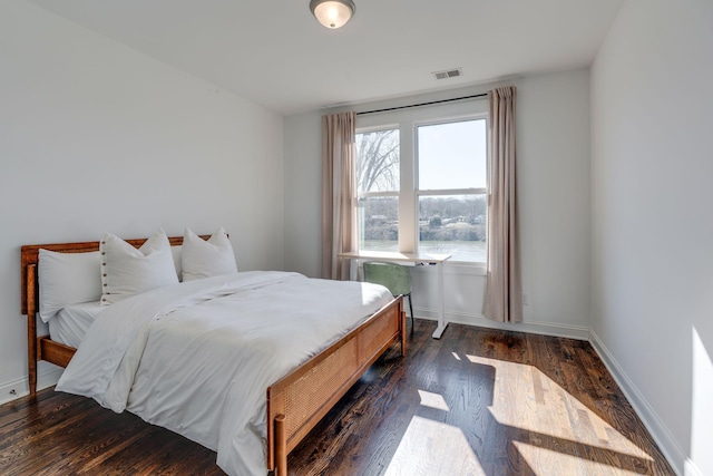 bedroom with dark wood-style floors, visible vents, and baseboards