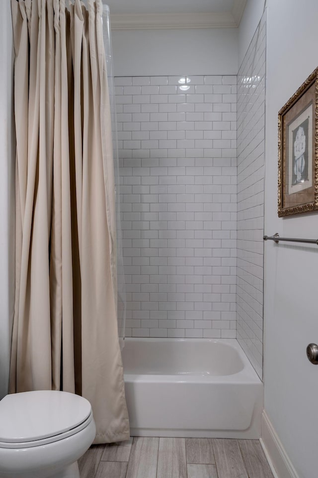 full bath featuring baseboards, wood finish floors, shower / bath combination with curtain, crown molding, and toilet