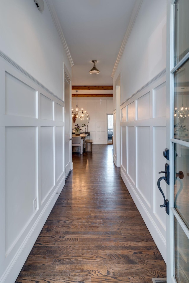 corridor featuring dark wood-style floors, ornamental molding, and a decorative wall