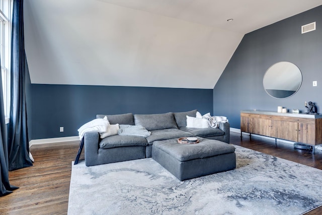 living area featuring visible vents, baseboards, lofted ceiling, and wood finished floors