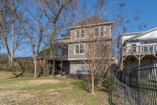 rear view of house with a yard, a balcony, and fence