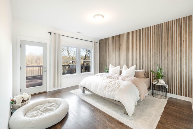 bedroom featuring wallpapered walls, baseboards, wood finished floors, and access to outside