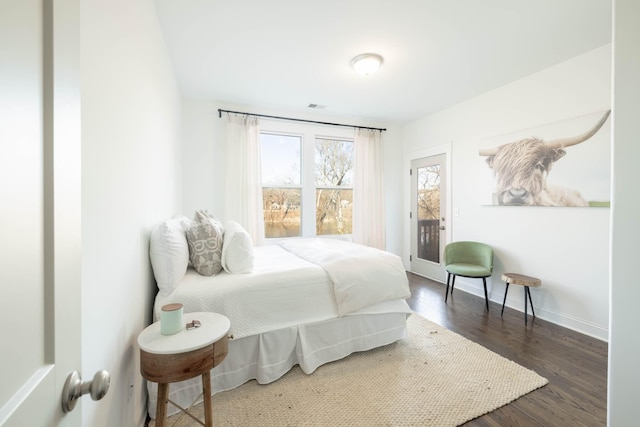 bedroom featuring dark wood-style floors, baseboards, visible vents, and access to exterior