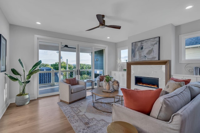 living area featuring baseboards, a ceiling fan, wood finished floors, a fireplace, and recessed lighting