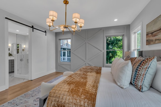 bedroom with a barn door, a notable chandelier, recessed lighting, a decorative wall, and wood finished floors