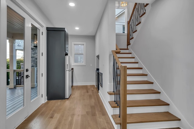 interior space featuring light wood finished floors, stairs, baseboards, and recessed lighting