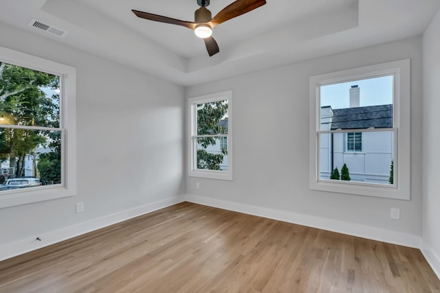 empty room with a raised ceiling, visible vents, and baseboards