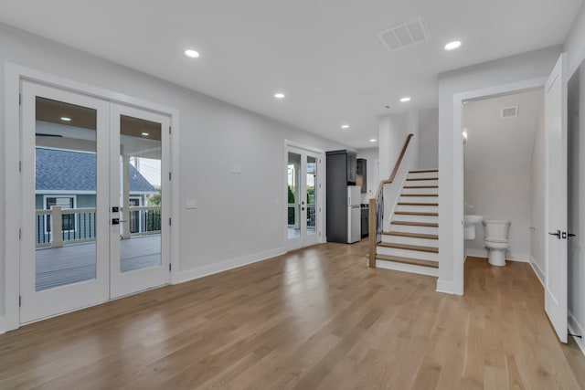 foyer entrance with visible vents, stairs, french doors, a wealth of natural light, and light wood finished floors