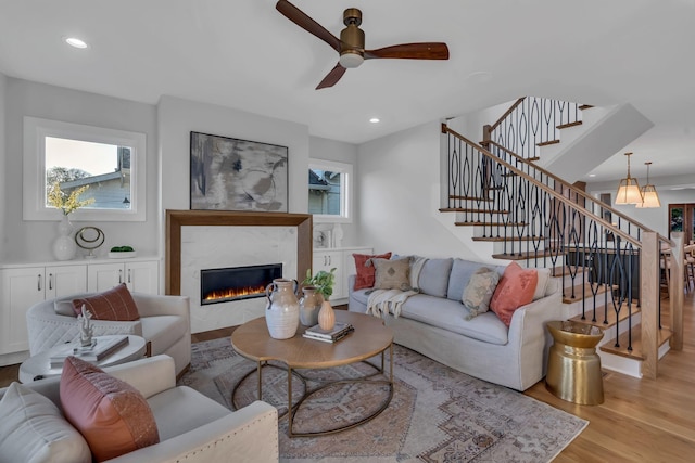 living room with stairway, light wood-type flooring, a tile fireplace, and a healthy amount of sunlight