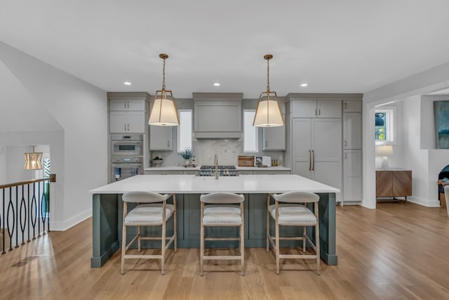 kitchen featuring tasteful backsplash, light countertops, a large island, and gray cabinetry