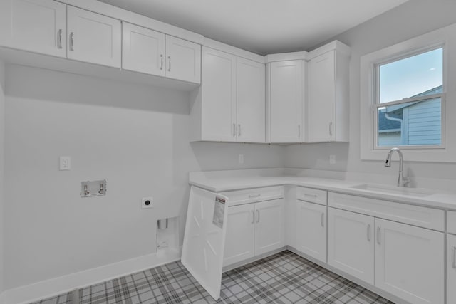 kitchen featuring light countertops, white cabinetry, a sink, and baseboards