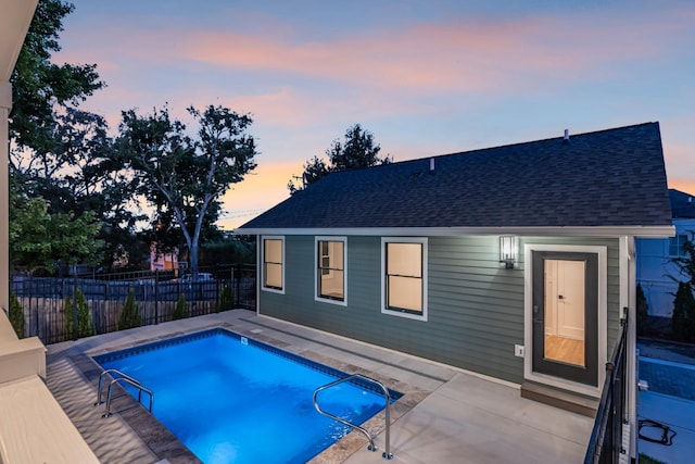 pool at dusk with a patio, fence, and a fenced in pool