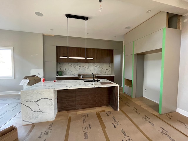 kitchen featuring tasteful backsplash, baseboards, a spacious island, modern cabinets, and a sink