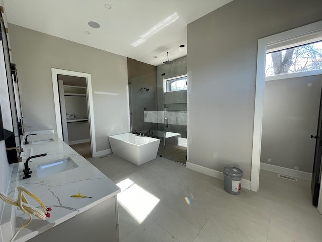 bathroom featuring a freestanding tub, a sink, baseboards, and walk in shower