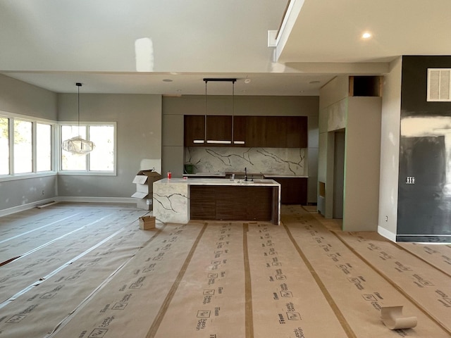 kitchen featuring a kitchen island with sink, visible vents, light countertops, tasteful backsplash, and modern cabinets