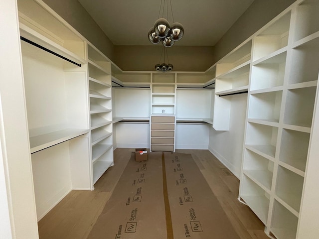 spacious closet featuring dark wood-style floors and a notable chandelier