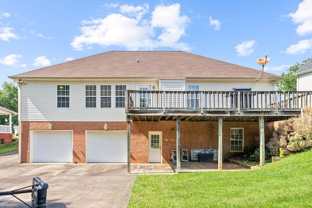 rear view of property featuring brick siding, a yard, concrete driveway, an attached garage, and a wooden deck