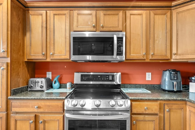 kitchen with stainless steel appliances, dark countertops, and brown cabinets