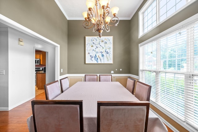 dining area with an inviting chandelier, baseboards, ornamental molding, and wood finished floors