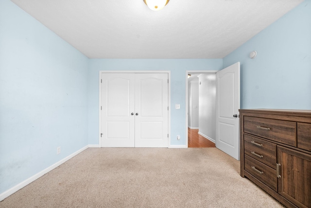 bedroom featuring baseboards, a closet, and light colored carpet