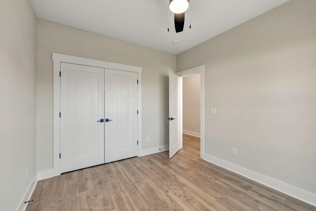 unfurnished bedroom featuring a closet, ceiling fan, light wood-style flooring, and baseboards