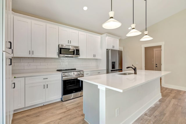 kitchen with light wood finished floors, appliances with stainless steel finishes, a sink, and tasteful backsplash