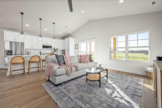 living area featuring recessed lighting, visible vents, vaulted ceiling, wood finished floors, and baseboards