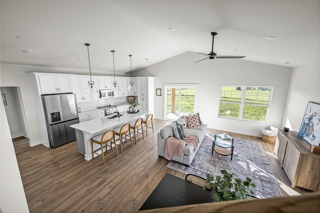 living room featuring lofted ceiling, dark wood-type flooring, a ceiling fan, and baseboards