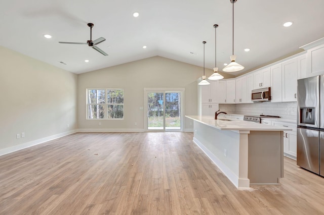 kitchen with light wood finished floors, tasteful backsplash, stainless steel appliances, light countertops, and a sink