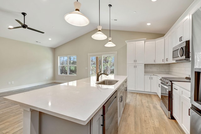 kitchen featuring stainless steel appliances, light wood-type flooring, a sink, and an island with sink