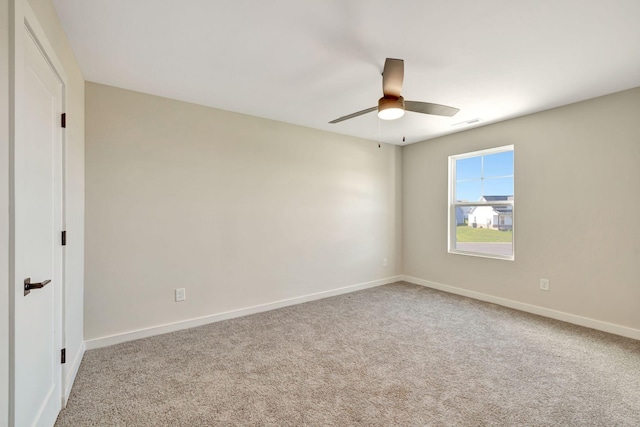 carpeted spare room with visible vents, baseboards, and a ceiling fan