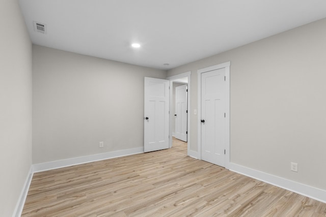 spare room with light wood-type flooring, baseboards, and visible vents